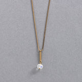 エシカルでサステナブルなジュエリーを提案するHASUNAのK18ブルームーンストーンのネックレス。チェーン、パーツ、金具はすべてK18製。チェーンは小さな箱型を組み合わせたベネチアンチェーンで、スライド式アジャスターなので好きな長さで調節が可能。チェーンの通した長さ約1㎝、幅約1mm程度の三角柱のバー型パーツの先にワイヤーで留めたブルームーンストーンが下がり、揺れます。ブルームーンストーンは濁りが非常に少なく、ほの青いストーンに青い輝きが入る美しいもの。ストーンの大きさは幅約4.5mm程度、高さ3mmほどの角のない平たい円柱のような形。普段から着けやすいサイズ感です。エシカル エシカルジュエリー HASUNA サステナブルHASUNA