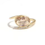 エシカルでサステナブルなジュエリーをご提案するHASUNAのオレゴンサンストーンダイヤモンドのK18製リング。約9.6×7.7mmのオーバル型のオレゴンサンストーンを横長になるようにセッティングし、周囲をぐるりと金の枠で囲んでいます。リングの指の腹側に来るところから、オレゴンサンストーンのてっぺんに向けて左側のアームが伸び、反対の右側のアームはオレゴンサンストーンの下を通り、サンストーンの4分の3くらいのところまで伸びています。ちょうど上下2本のラインがストーンを抱え込むような感じです。下のラインには外側から内側に向かい大から小へとグラデーション状に、直径1.2mm×2,1.1mm×2、1mm×2、0.9㎜×1のダイヤモンドが留まっています。地金はすべてK18 で、細かなスクラッチの入ったマット加工が施されています。腕の最大幅は1.3mm、厚みは1.5mmです。石座の高さは約5.8mm。重量は3.2g、ダイヤは0.04ctです。好きなルースを選んでサイズを指定してお作りするセミオーダーリングなので、重量、石座の高さ、石サイズは石により変化します。エシカル サステナブル エシカルジュエリー ハスナ HASUNA