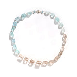 エシカルでサステナブルなジュエリーをご提案するHASUNAのアクアマリンとトパーズのネックレス。金具、パーツはSV925,ワイヤーは真鍮。
引き輪の横、直径約6mm程度、高さ約2mm程度のアクアマリンのビーズ。そこから表面を直線的に切り落としていったようなラフなランダムカットで、一見四角柱に見える多面体のアクアマリンが9個、同じ形のトパーズが6個、オーバルのナゲット基調のフォルムで表面に細やかなカットの入ったトパーズが5個、同形のアクアマリンが5個、引き輪横と同じアクアマリンビーズが1石、約b5mm四方で中央に直径4mm程度の丸い穴が空いた正方形のパーツが1つ、すべてワイヤーのシャンク留めで繋がったネックレス。全長約38cm。重さ約31g。
パキスタン、フンザ地方で採掘、研磨された宝石を使用。パキスタン フンザ エシカル 職業支援 女性支援 フェアトレード