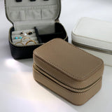 エシカルでサステナブルなジュエリーをご提案するHASUNAのこだわりを詰め込んだジュエリーケース。大きさは約6×10cm、高さは5cm程で、ちょうど高さの中央にあたる位置に3辺をぐるりと開けられるファスナーがついていています。素材は自然由来成分65%を使用し、耐久性があり経年劣化や色移りもしづらく、シボ調で仕上げられた高級感のあるヴィーガンレザー。ファスナーを開けると蓋になる部分の内側に三か所のネックレス類をかけられるボタン式の留め具があり、その下にネックレストップを受け止めるポケットがあります。本体内部は中央で仕切られ、左側にはリングやイヤリング、ピアスを差し込める4列のスリット、右半分はさらに中央で仕切りがあり、例えばブローチや大き目のジュエリーなどを入れられるようになっています。ケースの背中に当たる部分にHASUNAのロゴ入り。ケースの外側は3色展開で、黒に近いネイビー、ホワイト、グレイッシュなベージュのトープから選べます。ジュエリーケース ジュエリーボックス ジュエリー収納 収納ボックス エシカル サステナブル エシカルジュエリー ハスナ