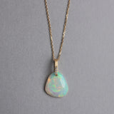 エシカルでサステナブルなジュエリーをご提案するHASUNAのK18製エチオピア産オパールとダイヤモンドのネックレス。チェーン、パーツはすべてK18製。チェーンは線径約0.25mmのアズキチェーンで、全長43cm。40cmと43cmの地点にマルカン式のアジャスターカンがあります。正面から見ると約1.5mm幅で長さ10mm程度の長方形に見えるバチカンは、後ろに折り返していて、横から見ると平たいDの字をアールが上、直線が下になるように転がしたような形をしています。Dの字の直線にあたるところに細い丸線が渡っていて、そこに直接穴を開けたオパールが通してあります。バチカンは正面下部に直径約1mmのダイヤモンドが縦に三個並んで留まっています。グリーンオニキスは不定形で、角の丸い縦長の三角形のような形状です。
オパール ダイヤモンド ネックレス K18 18金 ギフト プレゼント ダイヤモンドネックレス ダイヤモンドジュエリー オパールジュエリー エシカル サステナブル エシカルジュエリー ハスナ HASUNAエチオピア産オパール ネックレス エシカルジュエリー HASUNA ハスナ