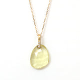 エシカルでサステナブルなジュエリーを提案するHASUNAの、レモンクォーツのペンダントタイプのネックレスです。Swingというコレクションのもの。幅1.5mm、縦約1㎝ほどの長方形の下部に3粒の直径1mmのダイヤモンドがとまっているK18の金具に、ストーンに直接穴をあけたレモンクォーツ(サイズ約10×12前後)が留まっています。枠や爪を使わず一点でつるすように留めているので、ストーンはよく光を通し、透明感が際立ちます。レモンクォーツのほんの少し苦みのあるレモンイエローがとてもきれいです。チェーン、金具はK18製。エシカルジュエリー ハスナ